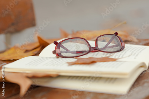 Book and red glasses on bench