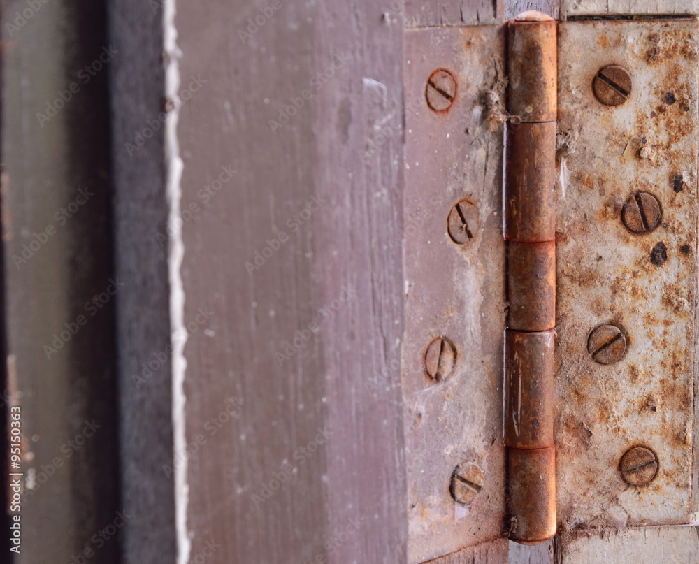 old and rusty door hinge on wooden frame