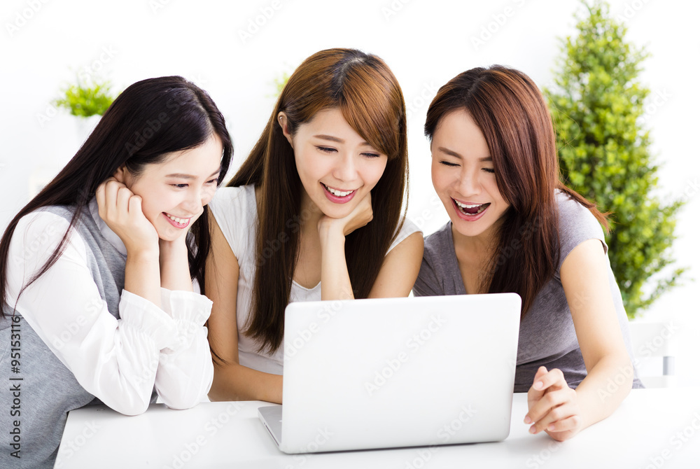 three happy young women watching laptop in living room three happy young women watching laptop in living room