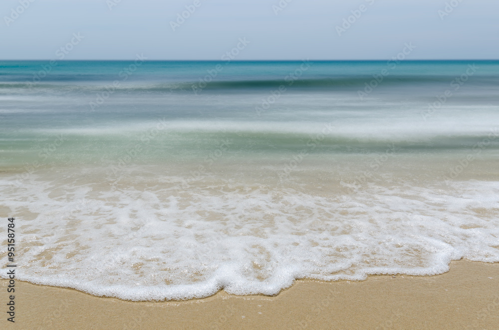 Seashore and smooth waves with sharp focus in foreground