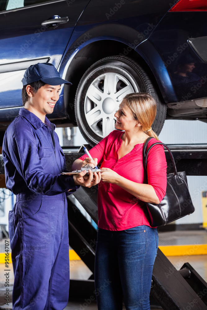 Customer Looking At Mechanic While Signing Document Customer Looking At Mechanic While Signing Document