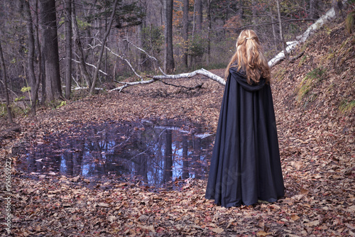 Girl wearing mantle standing by the water