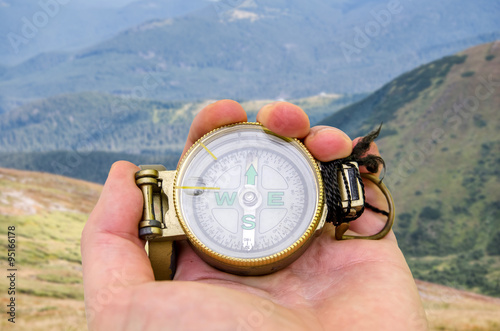 Compass in the hand against mountain photo