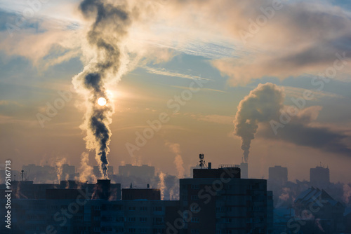 Environmental pollution. It is very cold in the morning sunrise in city, smoking chimneys.