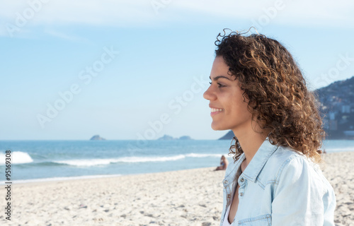 Junge Frau aus Südamerika schaut lächelnd aufs Meer