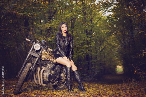 Biker girl in a leather jacket on a motorcycle posing in nature © czamfir