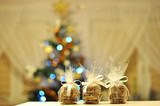 Domowe, świąteczne pierniki w ozdobnych paczuszkach na tle choinki