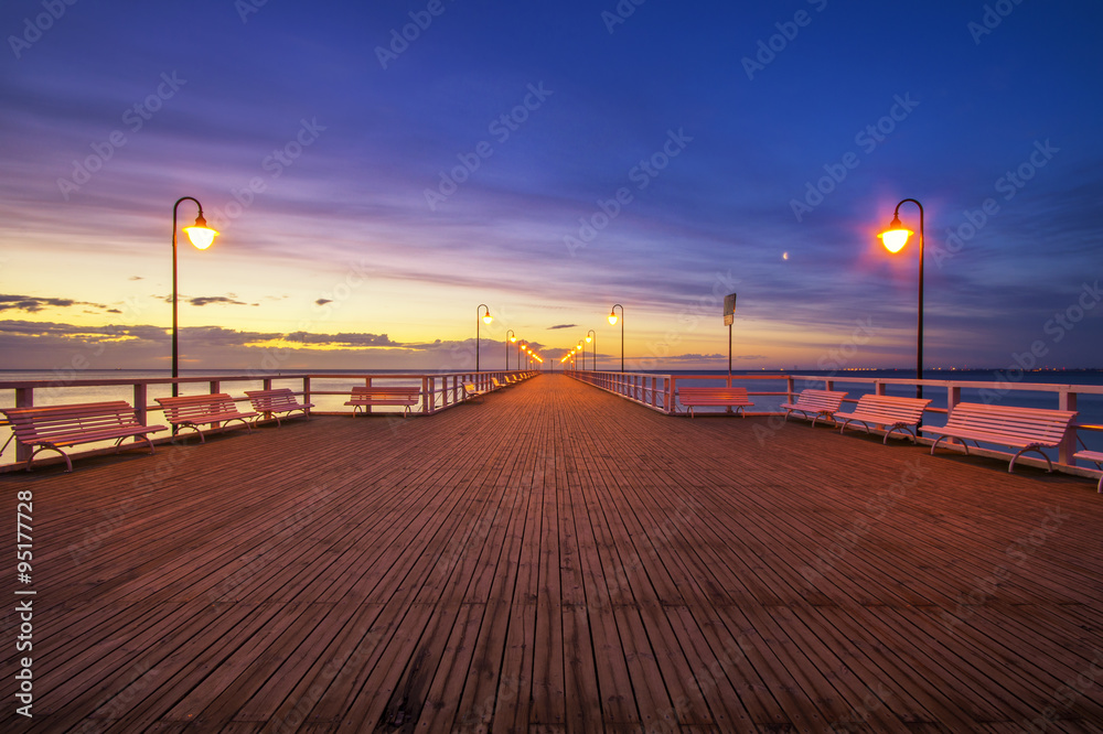 wooden pier by the sea lit by stylish lamps at night 