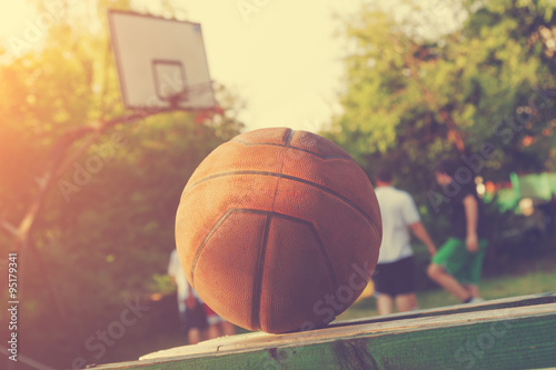 Basketball ball on a bench with defocused players in the background. © astrosystem