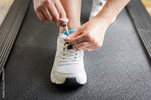 Person fastens his shoe before start to run on the treadmill