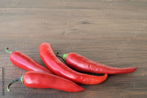 Red pepper. On wooden surfaces are four pods of red hot pepper.