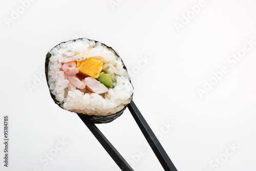 Sushi roll with black chopsticks isolated on white background.