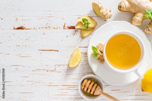 Ginger tea and ingredients on white wood background