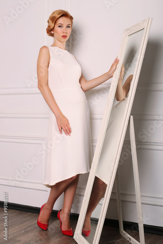 young woman with blond hair in retro style,wears elegant white dress