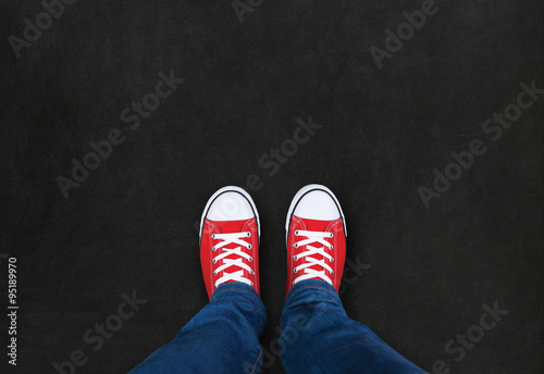 Feet wearing red shoes on black background with space for text photo