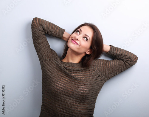 Happy smiling young woman in warm sweater looking up with hands