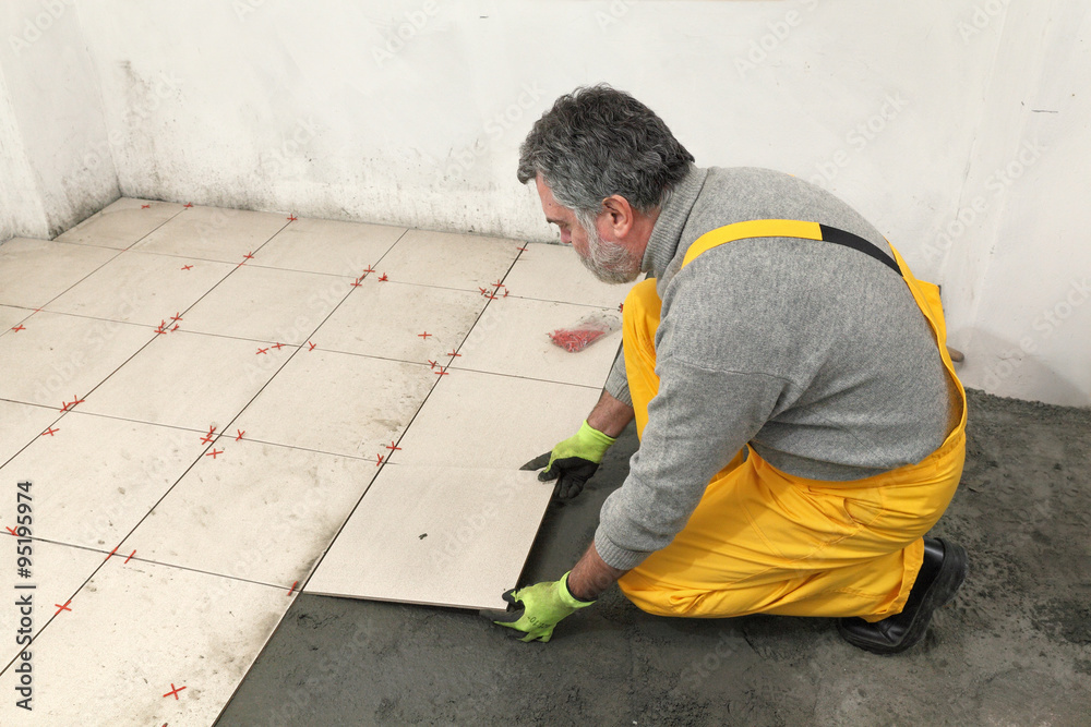 Home renovation, worker placing tiles to mix of sand and cement