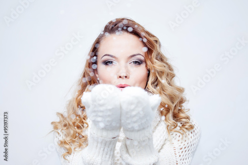 Woman Blowing Snow, girl in  warm knitted scarf and gloves, portrait on  white background, place for your text