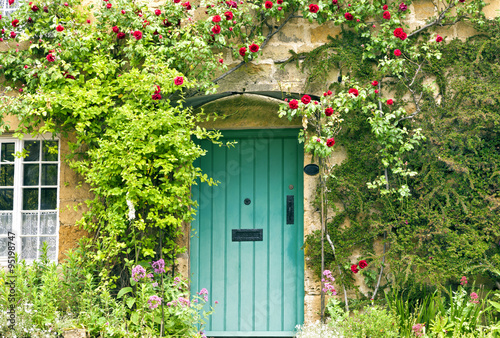 Photos Green wooden doors in an old traditional English stone cottage surrounded by cli