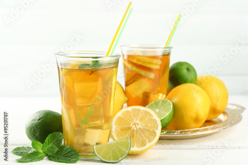 Iced tea with lemon on light wooden background