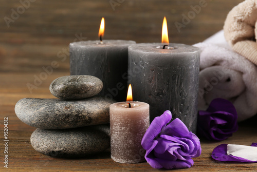 Alight wax grey candles with flowers  towels and pebbles on wooden background - relax set