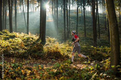 man running in the autumn forest with morning sun rays
