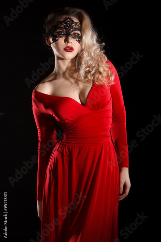 Young lady in a red evening dress and a black mask