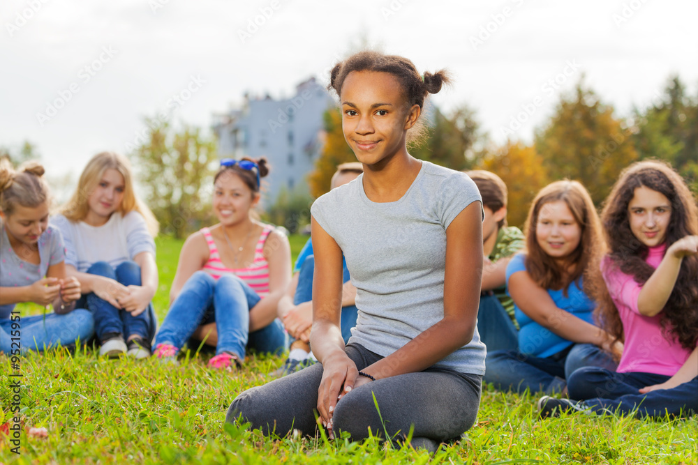 African girl and friends sitting on green meadow African girl and friends sitting on green meadow