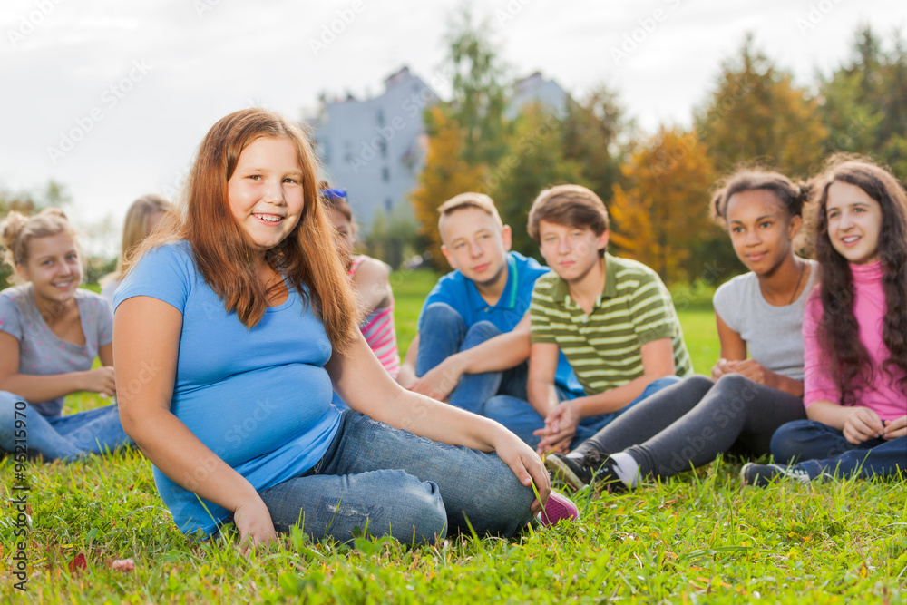 International friends sit together on green meadow