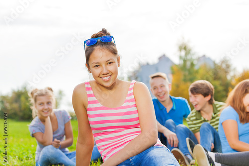 Asian girl and friends sitting together in park