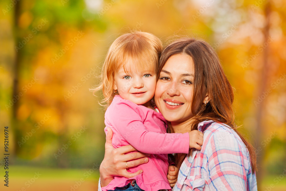 Happy mom and little blond portrait in autumn park