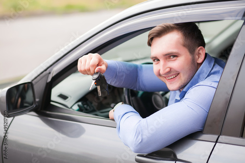 Young man sitting in car holding car keys