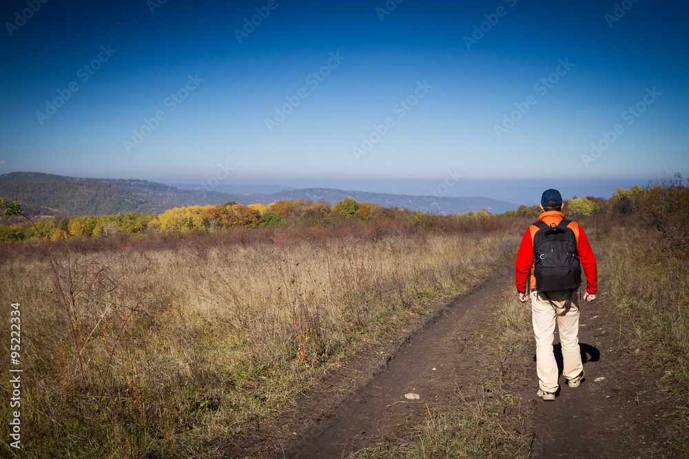 Male tourist with backpack is on a rural road