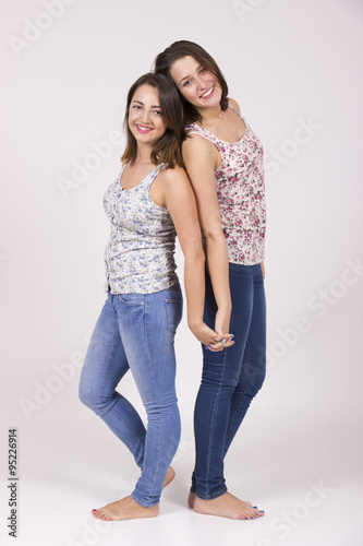 Two lookalike sisters, cute and intimate portrait in studio