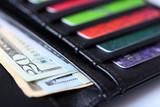 Black leather wallet with colourful credit cards and money, close up