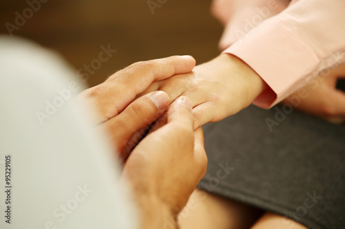 Concept of support - man and woman holding hands in the light room