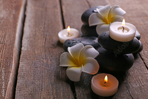 Relaxing composition with exotic fragipani flower  pebbles and candles on wooden background