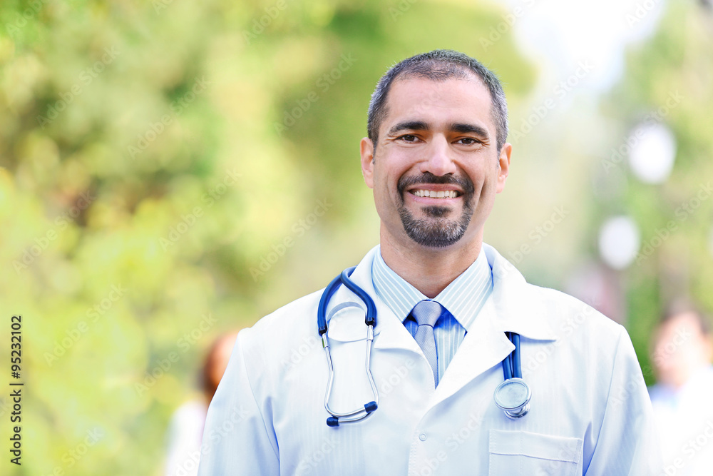 Happy doctor against unfocused medical team, outdoors Happy doctor against unfocused medical team, outdoors
