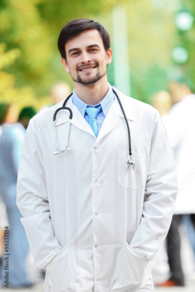 Smiling doctor with medical stuff behind, outdoors Smiling doctor with medical stuff behind, outdoors
