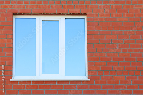 Part of red brick wall and blue window with double glazing 