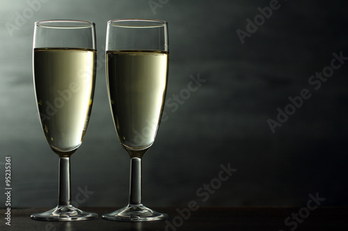 champagne glasses on wooden table on grey background
