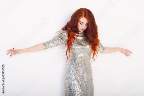 Beautiful young girl with red hair and shiny silver dress