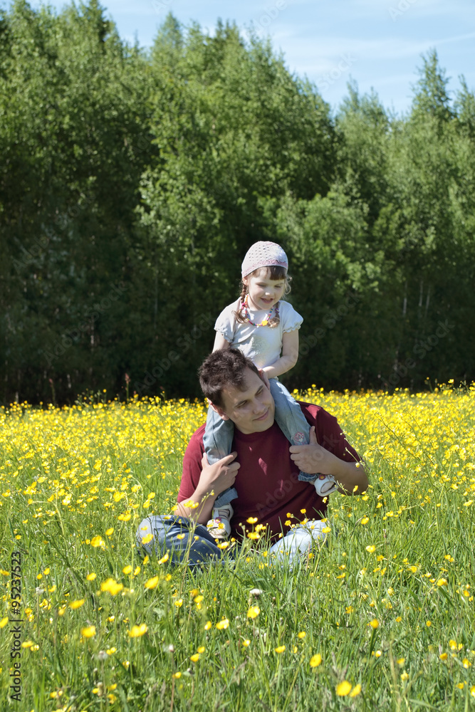Fototapeta premium Happy father with his daughter on shoulders among yellow flowers