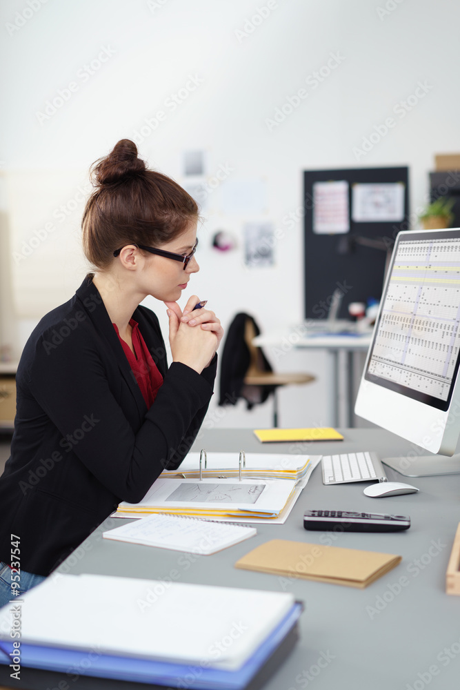 konzentrierte mitarbeiterin im büro schaut auf computer konzentrierte mitarbeiterin im büro schaut auf computer