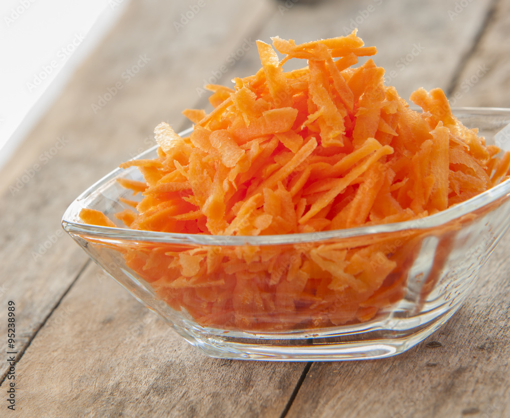 Grated carrots in bowl close up Grated carrots in bowl close up