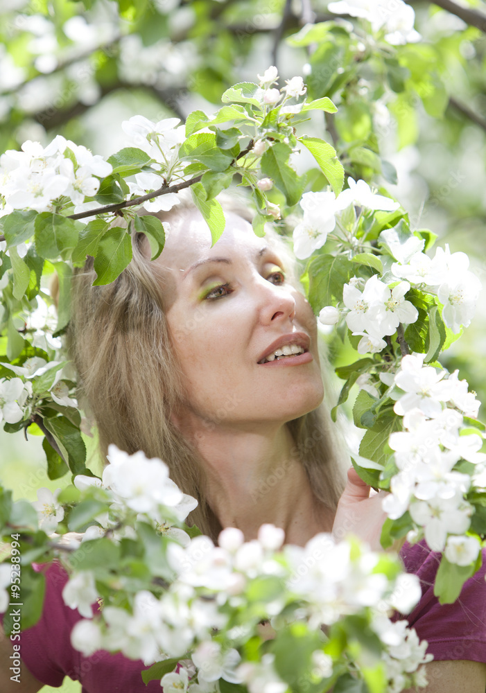 young attractive woman standing near the blossoming apple tree young attractive woman standing near the blossoming apple tree