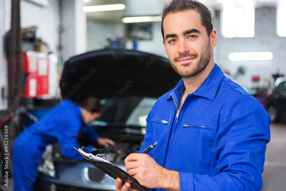 Young attractive mechanic working at the garage - obrazy, fototapety, plakaty 