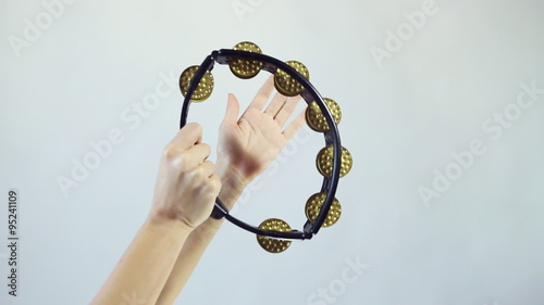 Hands playing on tambourine (shaker), shake several times on white background photo