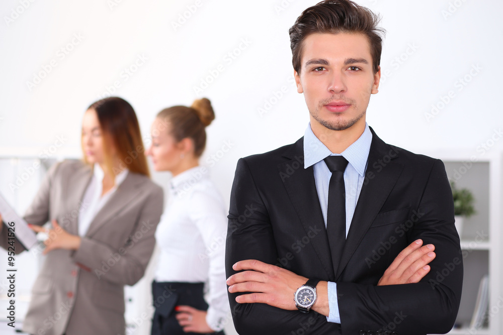 Cheerful business man in office with colleagues in the background, sturt up team Cheerful business man in office with colleagues in the background, sturt up team