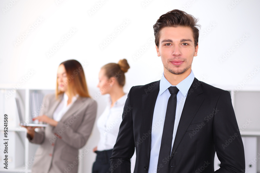 Cheerful business man in office with colleagues in the background, sturt up team Cheerful business man in office with colleagues in the background, sturt up team